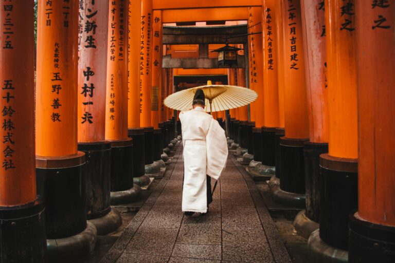 Person holding an umbrella under torii gates