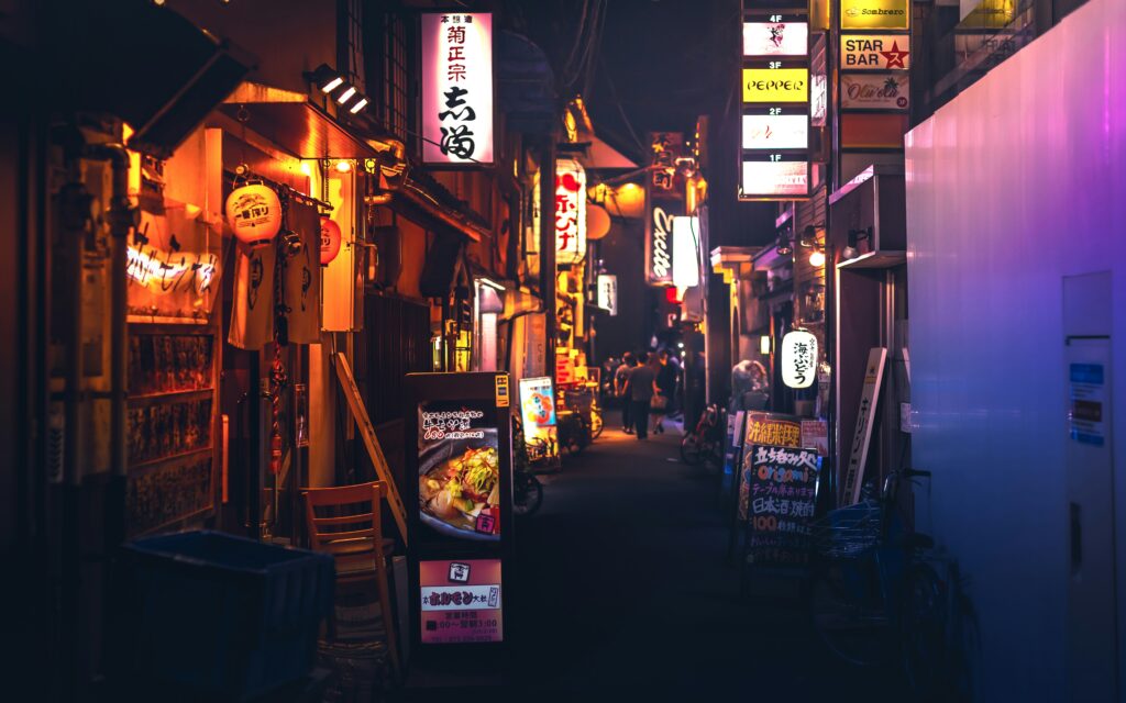 Night scene on a Kyoto street, showcasing a vibrant array of lit-up bars and restaurants.