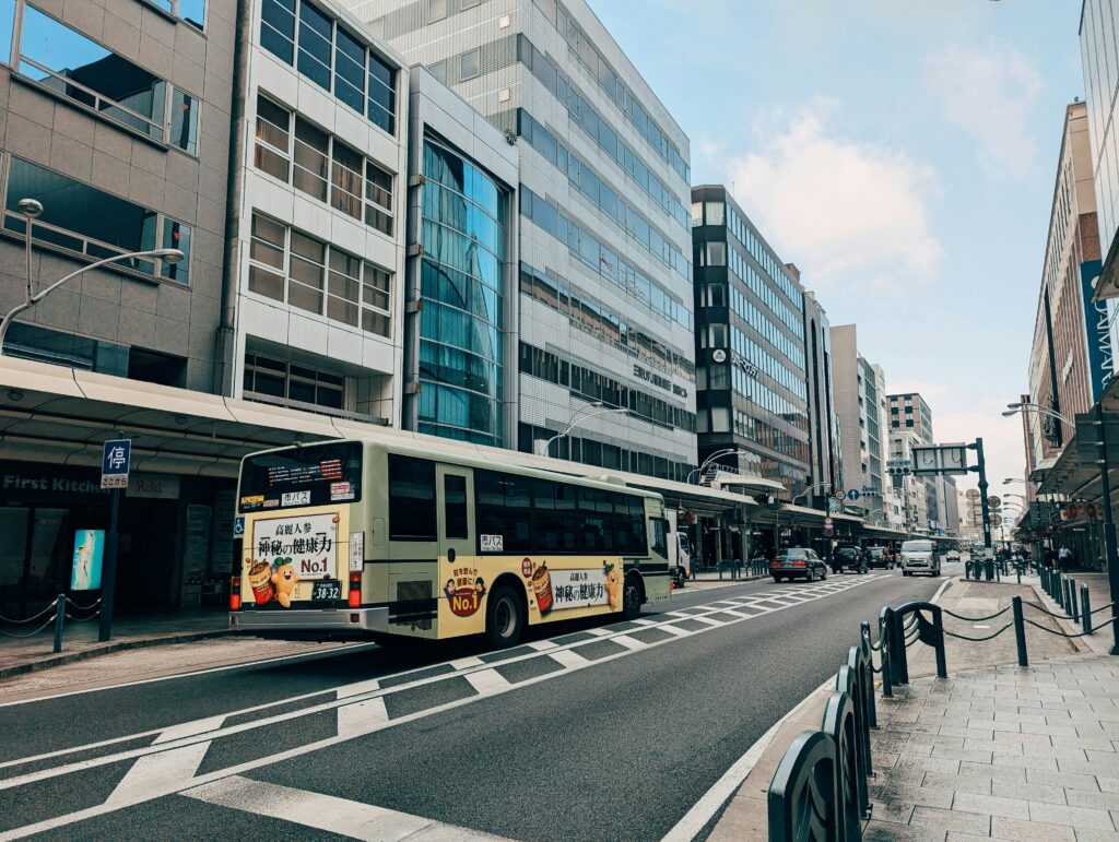 A Kyoto city bus drives down a modern part of downtown Kyoto.