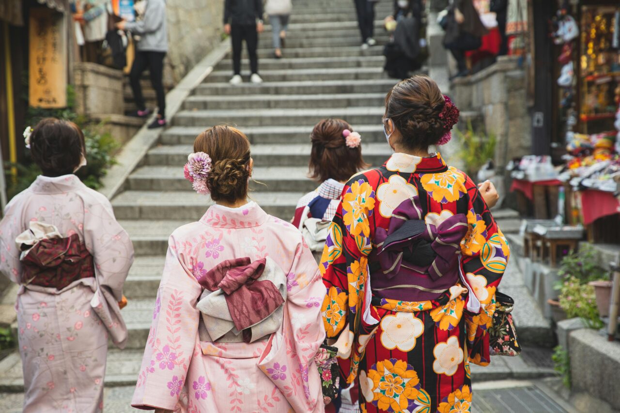 People in patterned kimonos walk the narrow streets of Kyoto