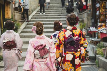 People in patterned kimonos walk the narrow streets of Kyoto