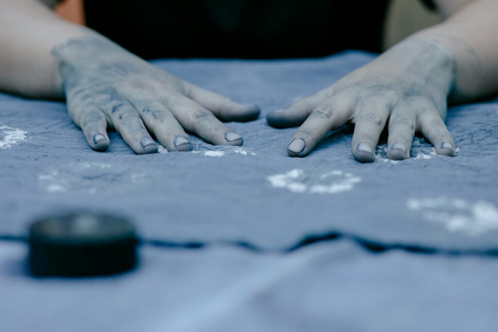A person with blue dye on their hands handles a piece of fabric