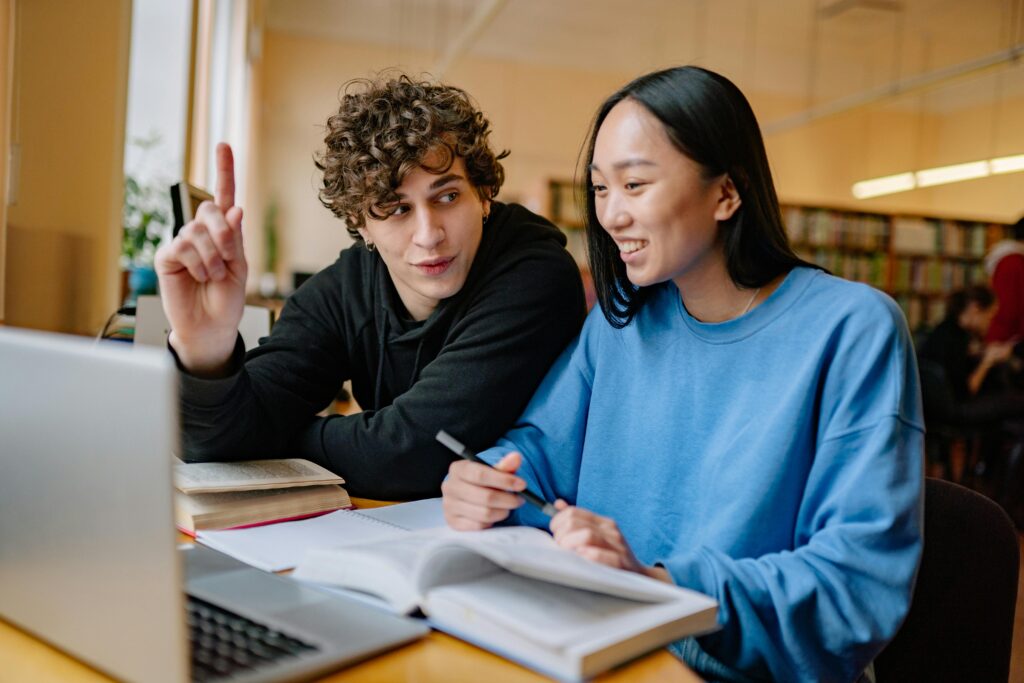 Students study in front of a laptop in a library